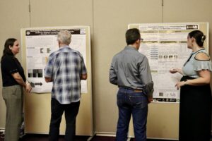 Four people looking at posters at the TAMUS High Explosives Workshop.