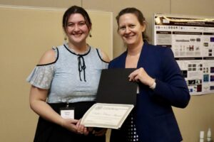 Two people holding certificates following an award ceremony.