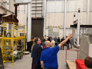Roughly 12 people standing inside of the laboratory at the Center for Infrastructure Renewal on the Texas A&M-RELLIS Campus in Bryan, Texas.