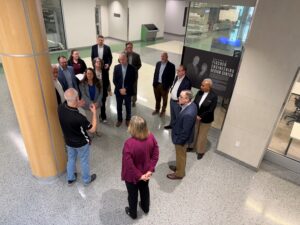 14 people standing in front of the Fisher Engineering Design center at Texas A&M University.