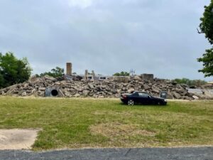 A black car parked in front of a rubble pile.